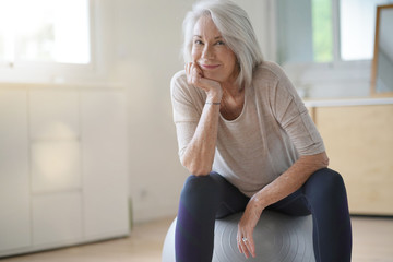 Older smiling woman sitting on pilates ball